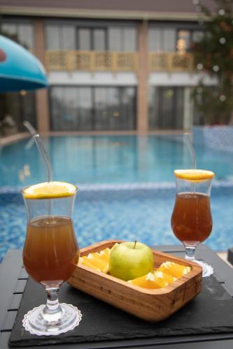 a tray of fruit and two drinks on a table next to a pool at Mandarinnart HOTEL in Astara