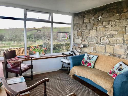 a living room with a couch and a stone wall at Leazes Cottage in Rothbury