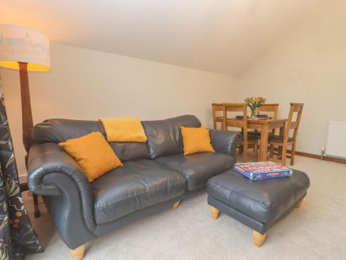 a living room with a leather couch and a table at The Coach House in Cheltenham