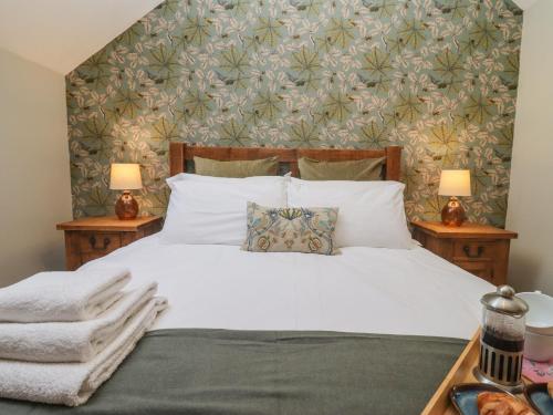 a bedroom with a white bed with a floral wallpaper at The Coach House in Cheltenham
