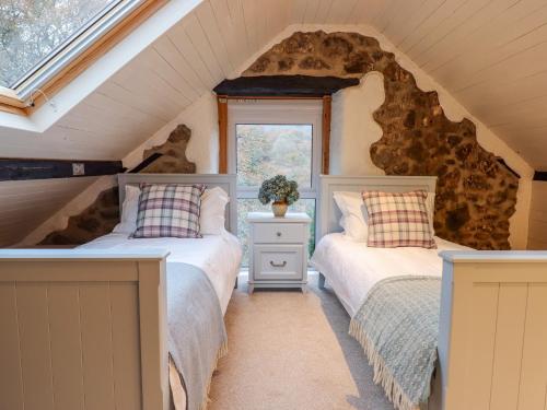two beds in a attic bedroom with a stone wall at Oakhurst in Newton Abbot