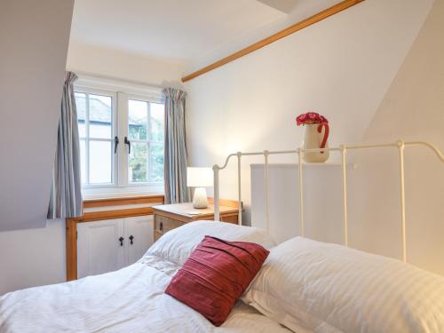 a bedroom with a bed with a red pillow on it at Waverley in Lyme Regis