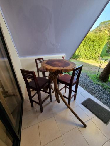 - une table et des chaises en bois dans une chambre avec fenêtre dans l'établissement Ballena Oasis Homes (Chalets con AC), à Uvita