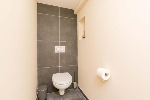 a bathroom with a toilet and a tiled wall at Vier Koningen in Zierikzee