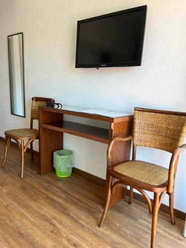 a desk with two chairs and a television on a wall at Hotel Tamariz in Piriápolis