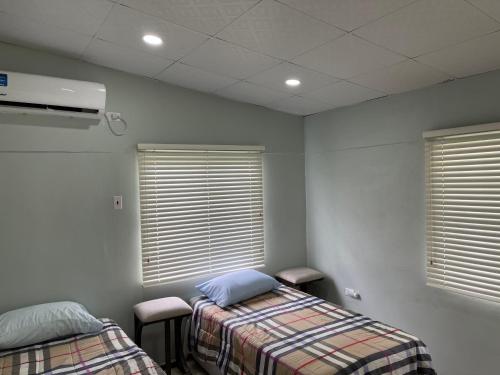 a hospital room with two beds and two windows at Beverley Manor DIAMOND VALE' 2 Bedroom 1 Bath Apartment in Diego Martin