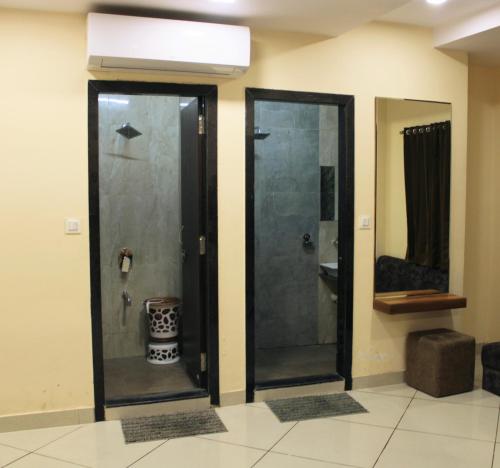 two glass doors in a bathroom with a shower at Maruti Group of Hotels - Shri Naman in Nāthdwāra