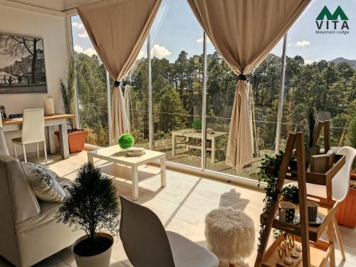 una sala de estar con una gran ventana con vistas a los árboles en Vita Mountain Lodge en Santa Lucía