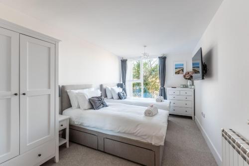 a white bedroom with two beds and a window at Azure in Bournemouth