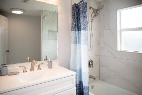 uma casa de banho branca com um lavatório e um chuveiro em Patio I Firepit I 65 TV w/ Netflix I 472mbps I WD em Vero Beach