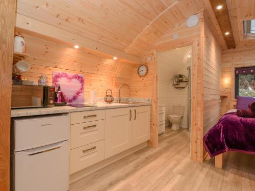 a kitchen in a log cabin with a sink and a toilet at Lovies Place - Crossgate Luxury Glamping in Penrith