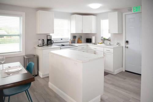 a kitchen with white cabinets and a table and a counter at Patio I Firepit I 65 TV w/ Netflix I 472mbps I WD in Vero Beach