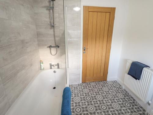 a bathroom with a shower with a bath tub at Olive Tree Cottage in Louth