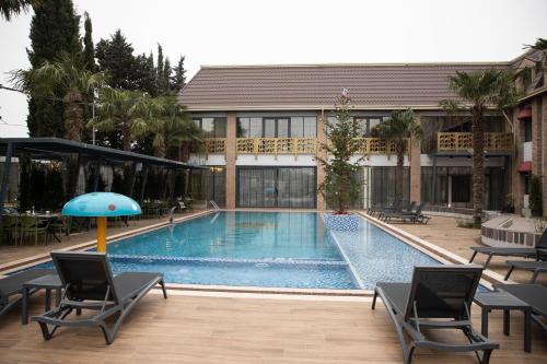 uma piscina com cadeiras e um guarda-sol ao lado de um edifício em Mandarinnart HOTEL em Astara