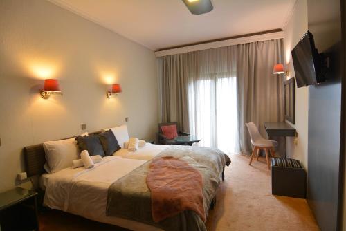 een hotelkamer met een groot bed en een televisie bij King Alexander in Florina