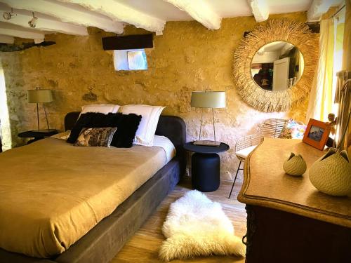 1 dormitorio con cama, espejo y alfombra en Gîte Les Pierres Blondes, en Groléjac