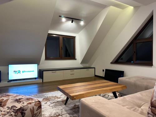 uma sala de estar com uma mesa e uma televisão em Apartman GLECER KOP em Kopaonik