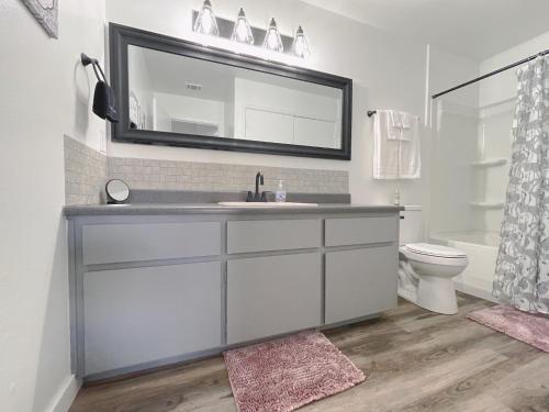 a bathroom with a sink and a toilet and a mirror at Lovely Apartment Unit Near Central Coalinga in Coalinga