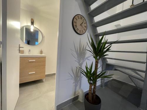 a bathroom with a staircase with a clock and a plant at Superbe T3 Duplex proche Paris & Disneyland in Ozoir-la-Ferrière