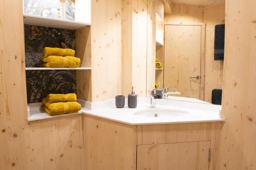a bathroom with a sink and yellow towels on shelves at Luxury romantic Roundhouse and hot tub for two in Glasgow