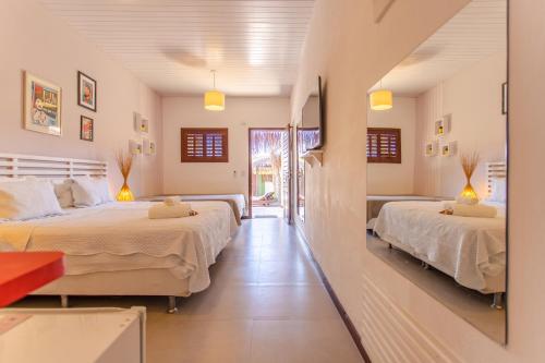 a bedroom with two beds and a mirror at Pousada La Vie Jeri in Jericoacoara