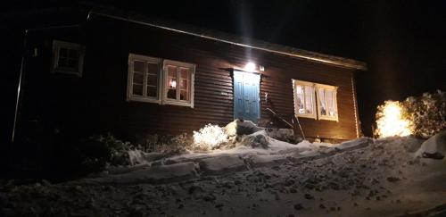 a house with a blue door in the snow at night at Stalheim Fjord og Fjellhytter in Stalheim
