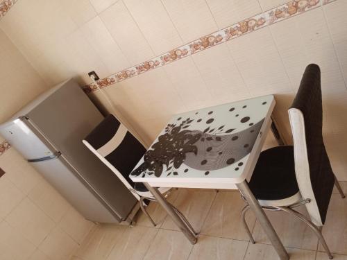 een tafel en stoelen in een kamer met een koelkast bij Résidence hôtelière Nour in Dakhla