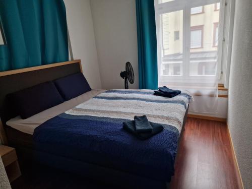 Schlafzimmer mit einem Bett mit blauer Bettwäsche und einem Fenster in der Unterkunft Swiss Holidays Apartment Rosenstrasse 10 in Interlaken