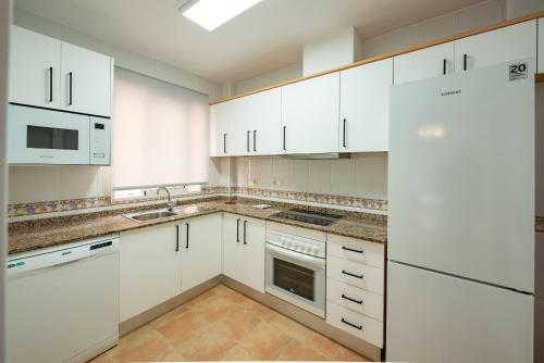 una cocina blanca con armarios y electrodomésticos blancos en Holiday Beach Brissa Mar, en Gran Alacant