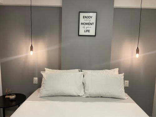 a bed with white pillows and a sign on the wall at Mardisa Design by Jess Hospedagens in João Pessoa