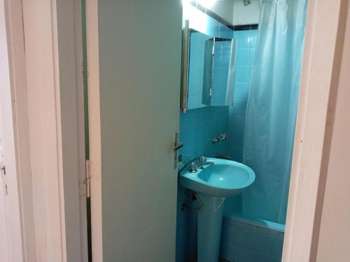 Baño azul con lavabo y espejo en Edificio Columbia, en Asunción