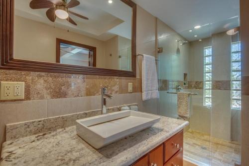 a bathroom with a sink and a mirror and a shower at Placencia Pointe Townhomes #8 in Placencia Village