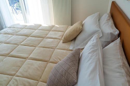 a bed with white sheets and pillows next to a window at Alloggio nuovissimo al centro e rilassante in Ischia