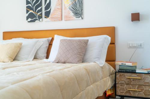 a bed with white pillows and a wooden headboard at Alloggio nuovissimo al centro e rilassante in Ischia