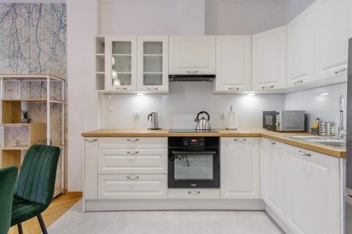 a white kitchen with white cabinets and appliances at KORNWALIA - stylowy apartament o wysokim standardzie w centrum Nowego Targu, z prywatnym, zadaszonym parkingiem in Nowy Targ