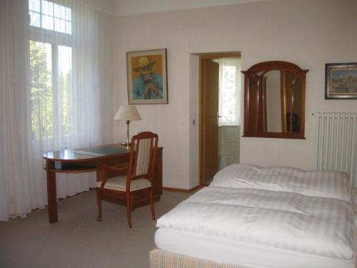 a bedroom with a desk and a bed and a table at Pension Thiel in Bad Schwartau