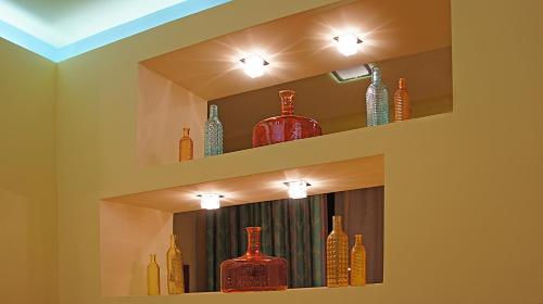 a shelf filled with glass vases on a wall at Chryssi Akti, Sure Hotel Collection in Batsi