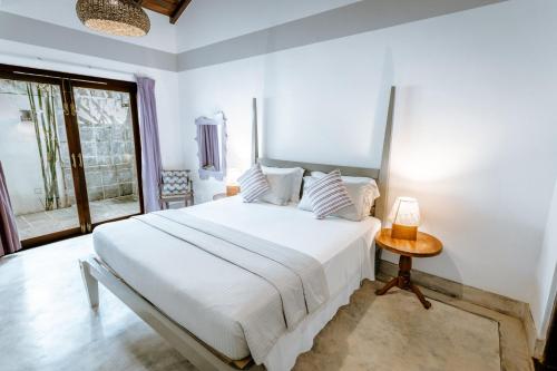 a white bedroom with a large bed and a table at Saltasia Boutique Beach Villa in Mirissa