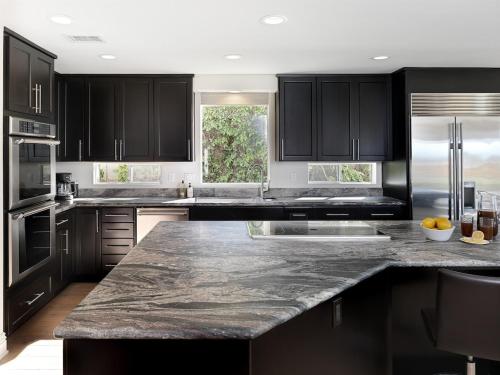 a kitchen with black cabinets and a granite counter top at Grandview Getaway, Luxury 4BR, Ocean View, Fire Pit in Encinitas