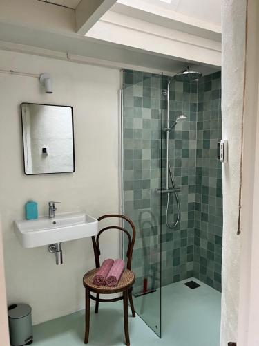 a bathroom with a sink and a shower and a chair at Little Secret Zeeland + ligbad in Schoondijke