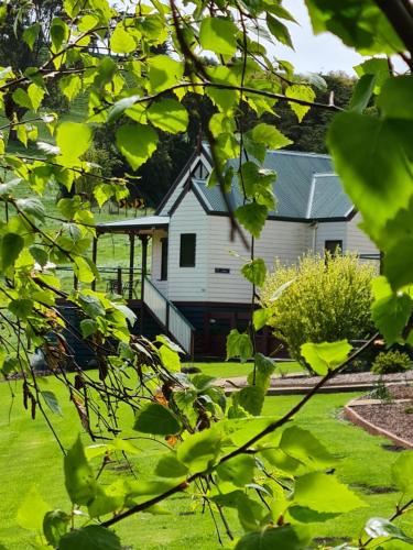 a house is seen through the leaves of trees at Maple Ridge Cottages in Dumbalk