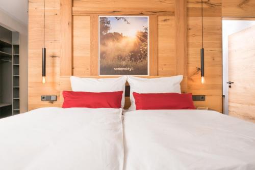 two beds in a bedroom with two red pillows at Chalet-Ferienwohnung Sonnenidyll, 51 qm, Wellness/Fitness/Sauna – Bergrödelhof in Feilitzsch
