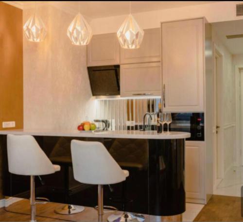 a kitchen with white cabinets and white bar stools at apartment tbilisi 5 star king david residence in Tbilisi City