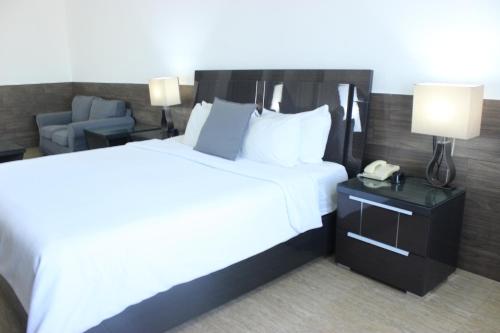 a hotel room with a large bed and a phone at Beverly Hills: Hotel and Business in San Salvador