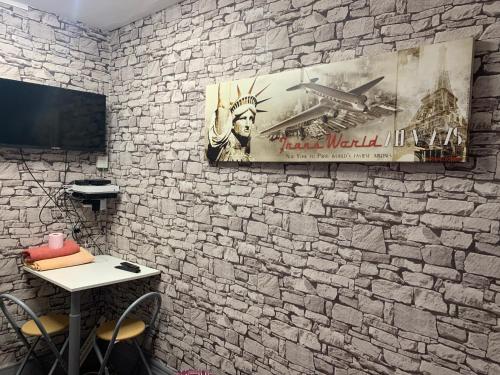 a room with a stone wall with a table and a poster at Au Coeur De Lyon in Lyon