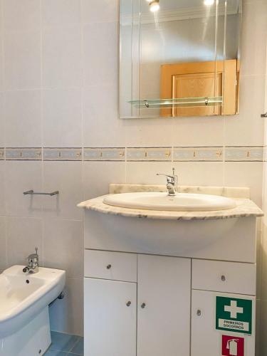 a white bathroom with a sink and a mirror at T1 Perto da Praia Nazaré -The PI House in Nazaré