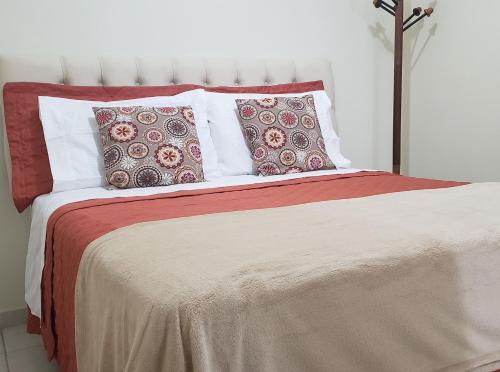 Cama con sábanas y almohadas rojas y blancas en 3QTS CENTRO PRAIA DO FORTE, en Cabo Frío