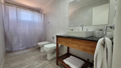 Baño blanco con lavabo y aseo en Complejo Altos La Caleta en Mar de Cobo