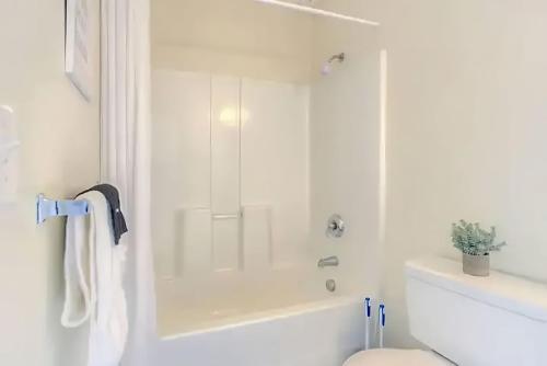 a white bathroom with a shower and a toilet at Perfect 1BR In Prime Location & View of Stadiums in Detroit