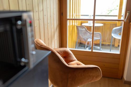a chair in a room with a balcony with a table at Apartmenthaus Matri by Pferd auf Wolke in Wald am Arlberg